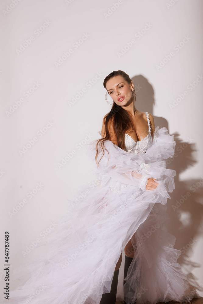 Beautiful woman in white fluffy fur coat and boots in studio. Long-haired brunette girl in lace pants. Gorgeous big lips and eyes. Portrait of pretty woman. Woman in white underwear Beautiful woman in white fluffy fur coat and boots in studio. Long-haired brunette girl in lace pants. Gorgeous big lips and eyes. Portrait of pretty woman. Woman in white underwear