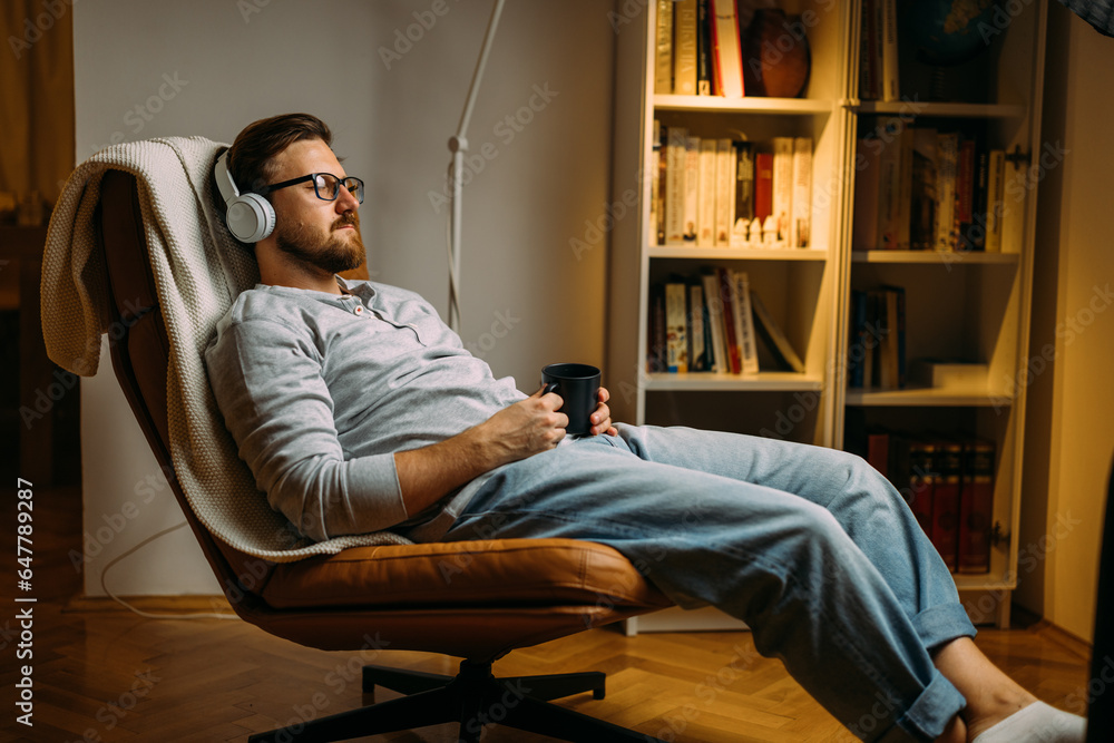 Caucasian man with eyes closed enjoying music with headphones while relaxing at home Caucasian man with eyes closed enjoying music with headphones while relaxing at home