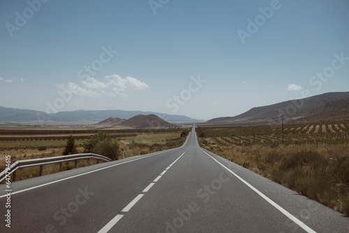 Autostrada spagnola vuota che attraversa un paesaggio andaluso con montagne in lontananza. photo