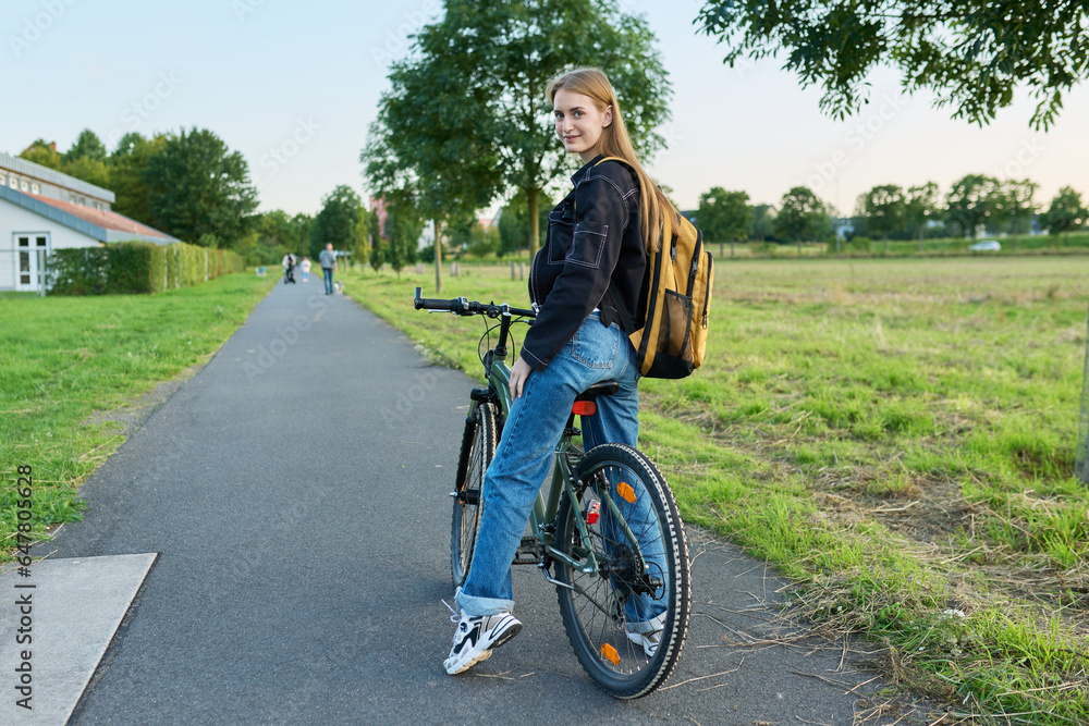 Portrait of teenage student girl with backpack on bicycle