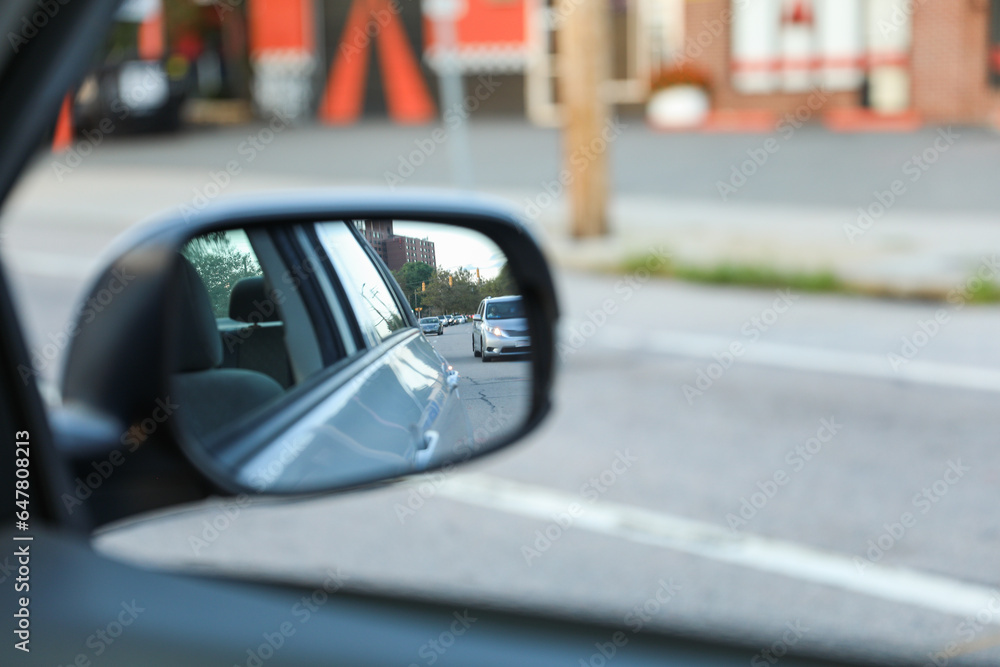 car's rearview mirror, reflecting a scenic road behind. The mirror symbolizes nostalgia, reflection, and the journey of life, capturing moments from the past