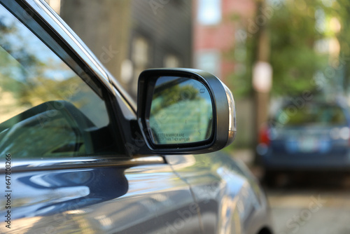 car\'s rearview mirror, reflecting a scenic road behind. The mirror symbolizes nostalgia, reflection, and the journey of life, capturing moments from the past