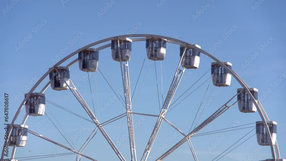 modern ferris wheel with closed cabins at carnival with blue sky no clouds in the background illuminated wide angle close up shot modern ferris wheel with closed cabins at carnival with blue sky no clouds in the background illuminated wide angle close up shot