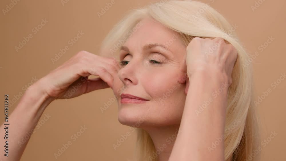 Close up female wrinkly smooth tighten face Caucasian mature senior 50s old woman touch perfect clean skin beauty anti-aging lifting cosmetics plastic surgery collagen rejuvenation on beige background