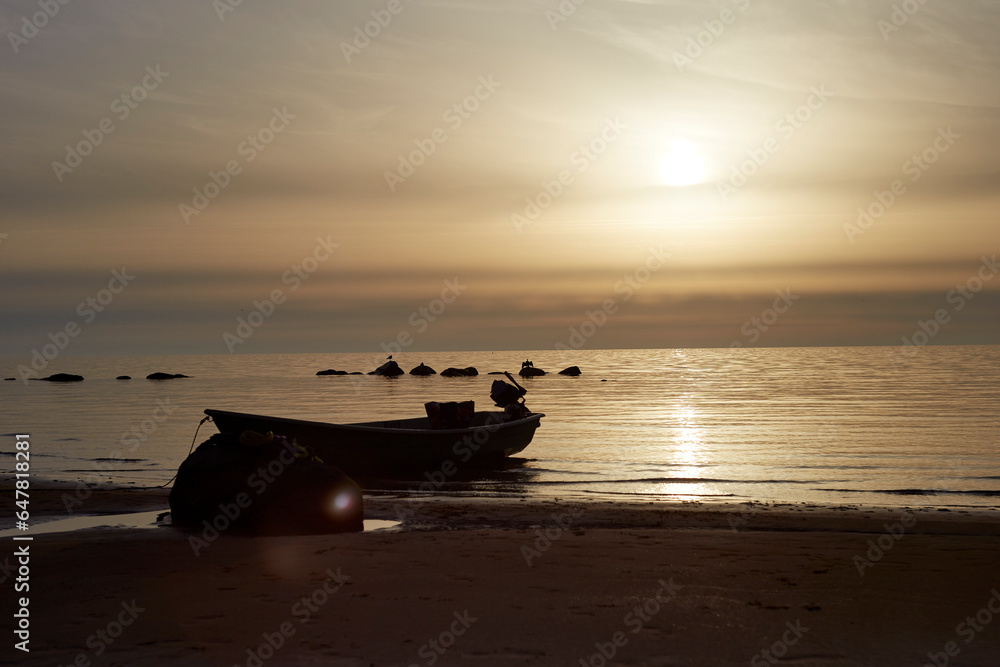 Beautiful landscape during the sunset with sky and sea coloured by the sunset and small boat on the shore Beautiful landscape during the sunset with sky and sea coloured by the sunset and small boat on the shore