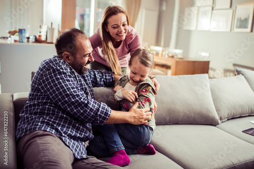 Young Caucasian family playing and having fun on the couch at home