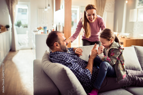 Young Caucasian family playing and having fun on the couch at home