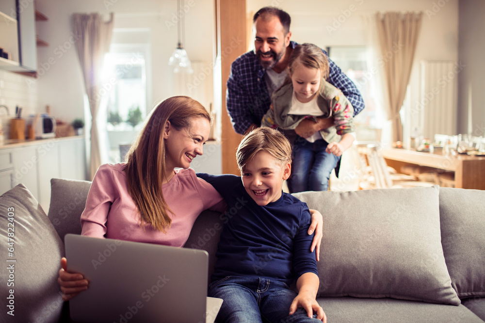 Young Caucasian family having fun and using a laptop at home Young Caucasian family having fun and using a laptop at home