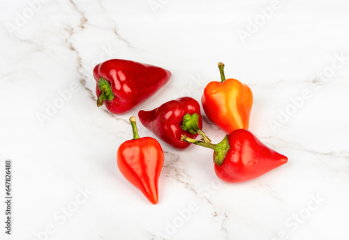Several pods of hot pepper on a light background.