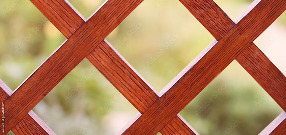 Wooden lattice, a decorative fence with garden on the background. Wooden lattice, a decorative fence with garden on the background.