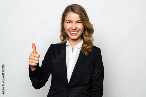 Businesswoman looking at camera in thumbs up greeting gesture, studio background 