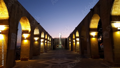 A majestic walkway  adorned with arches and lights  glows brilliantly at night  beckoning visitors to explore its beauty..