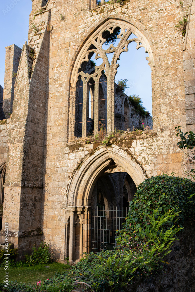Detail of the main facade of Beauport Abbey, a roofless gothic building located in Paimpol, Cotes d'Armor, Brittany, France. August 2023, sunset view.