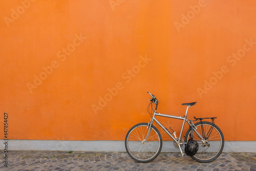 Black bicycle parked next to concrete orange wall. Banner, copy space. High quality photo