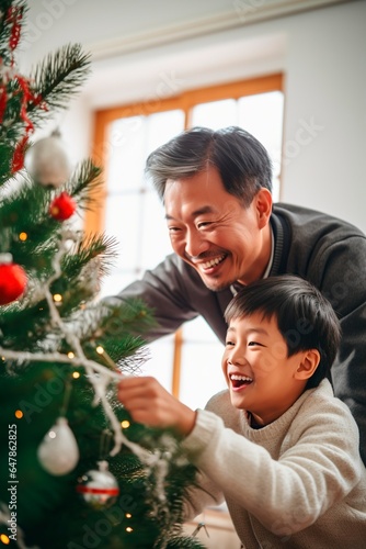 Chinese American grandfather decorating Christmas tree with his grandson