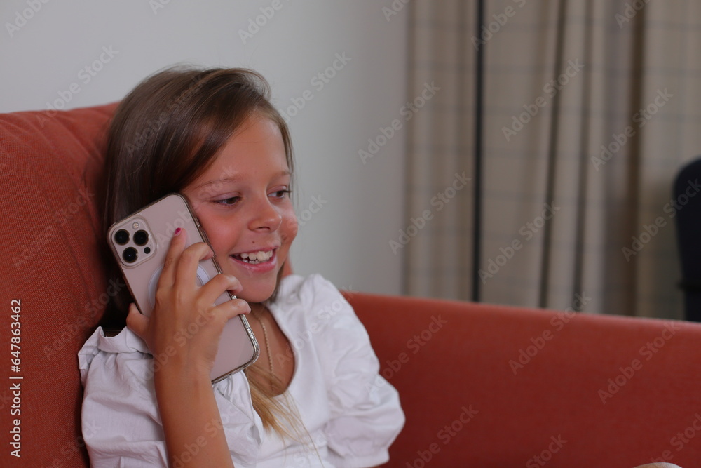 Child girl sitting on sofa talking by smartphone, lifestyle Child girl sitting on sofa talking by smartphone, lifestyle