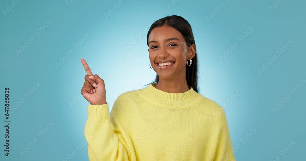Face, woman and advertising presentation in studio of deal, information and choice on blue background. Happy portrait, indian model and pointing to mockup space, announcement and launch of promotion Face, woman and advertising presentation in studio of deal, information and choice on blue background. Happy portrait, indian model and pointing to mockup space, announcement and launch of promotion