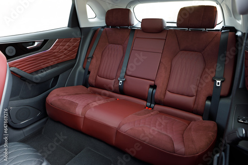 Modern car interior - three rear red leather seats with the seat belts 