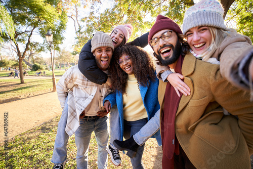 Quadro su tela Winter selfie group excited friends smiling at camera in park on sunny day