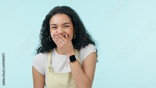 Laughing, funny and a young woman in studio with a joke, carefree humor and good mood. Face of a gen z girl with hand, giggle and portrait on a blue background for fun energy, fashion and reaction