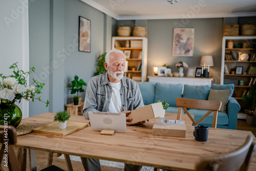 senior man sit at home hold post package delivery present or order