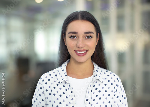 Portrait of happy woman in office. Pretty girl looking at camera and smiling on blurred background
