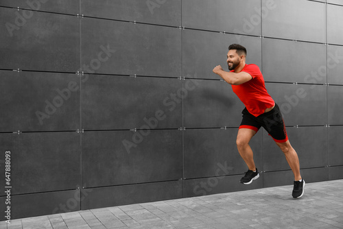 Happy man running near building outdoors. Space for text