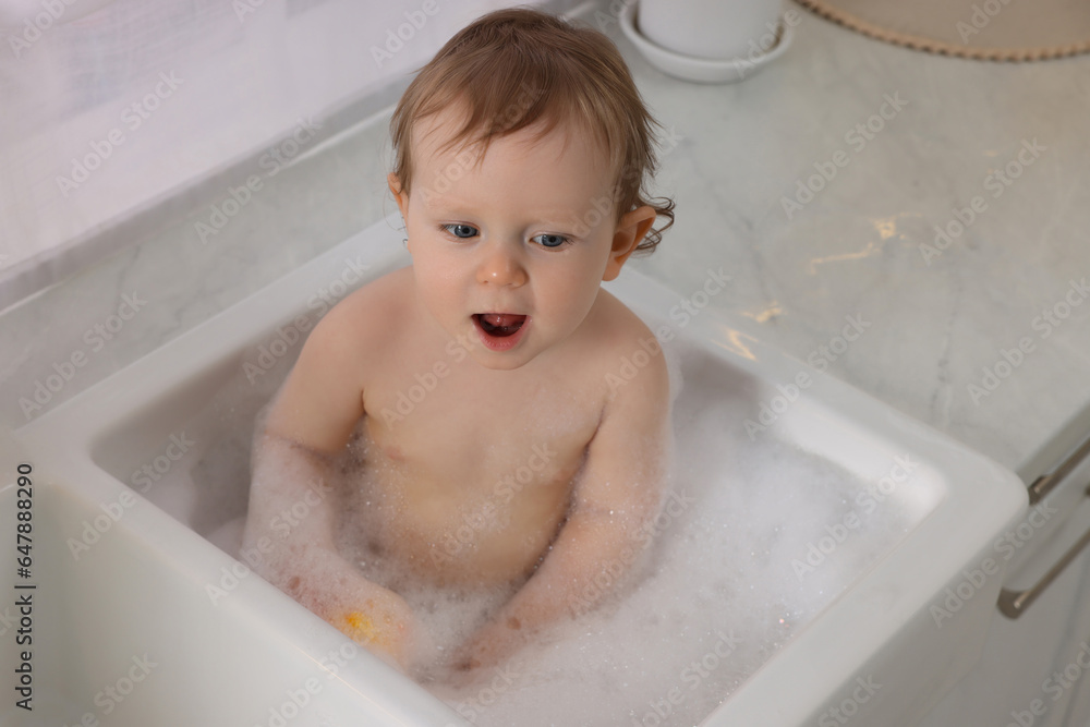 Cute little baby bathing in sink indoors Cute little baby bathing in sink indoors