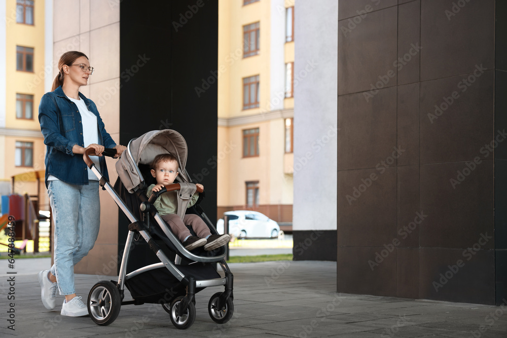 Beautiful nanny with cute little boy in stroller walking outdoors, space for text Beautiful nanny with cute little boy in stroller walking outdoors, space for text