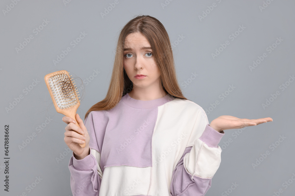 Upset woman holding brush with lost hair on light grey background. Alopecia problem Upset woman holding brush with lost hair on light grey background. Alopecia problem