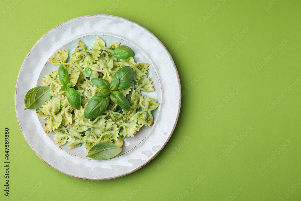 Delicious pasta with pesto sauce and basil on light green background, top view. Space for text Delicious pasta with pesto sauce and basil on light green background, top view. Space for text