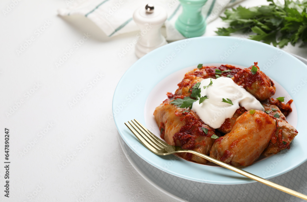 Delicious stuffed cabbage rolls served with sour cream on white table, closeup. Space for text Delicious stuffed cabbage rolls served with sour cream on white table, closeup. Space for text