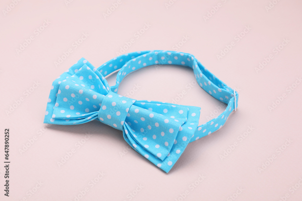 Stylish light blue bow tie with polka dot pattern on beige background Stylish light blue bow tie with polka dot pattern on beige background