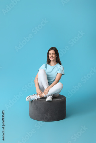 Young woman sitting on pouf...