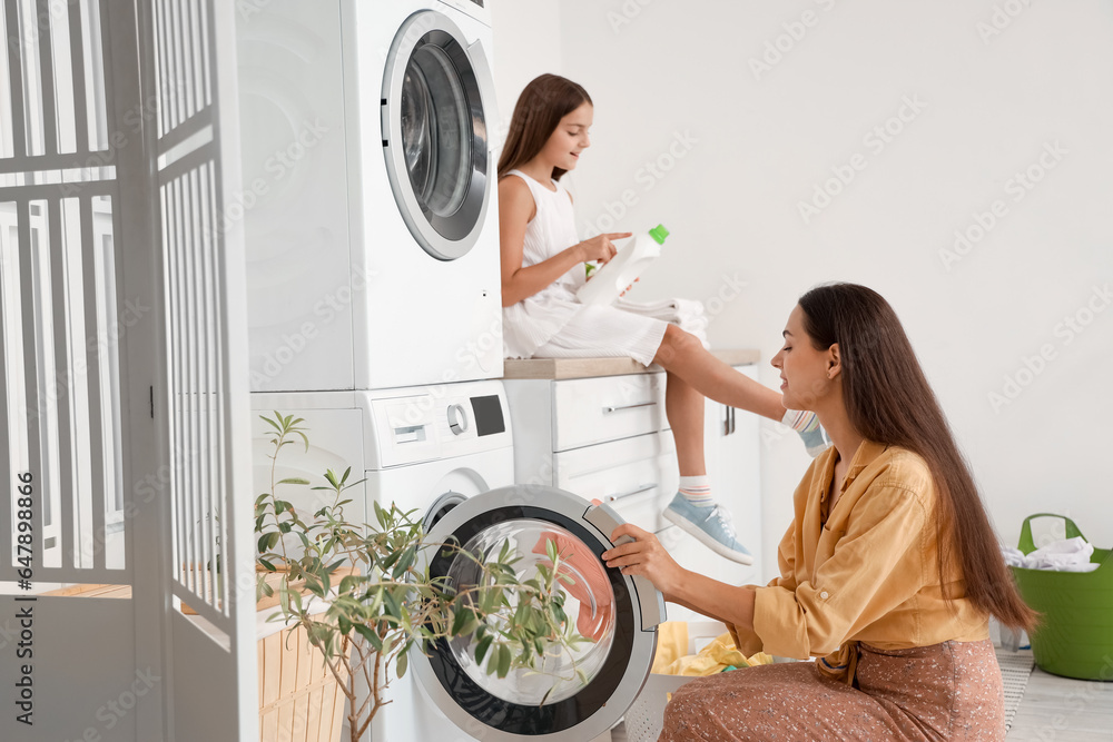Happy mother with her little daughter doing laundry at home - obrazy, fototapety, plakaty 