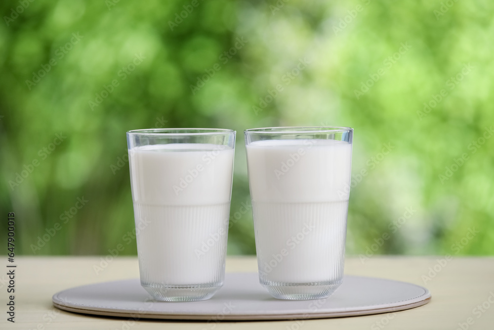 Glasses of fresh milk on yellow wooden table outdoors Glasses of fresh milk on yellow wooden table outdoors