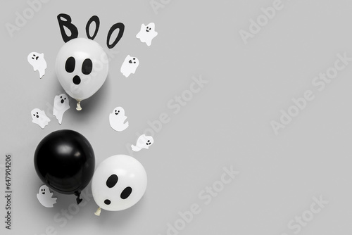 Word BOO with different funny Halloween balloons and paper ghosts on grey background