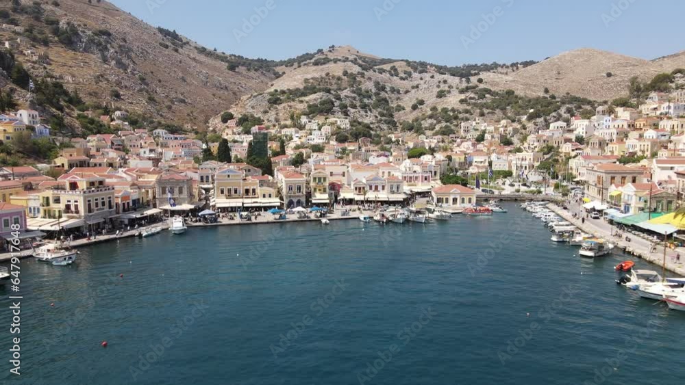 Cinematic aerial from the city Symi in Greece to a large yacht leaving port Cinematic aerial from the city Symi in Greece to a large yacht leaving port