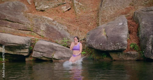 girl dives into lake by jumping off a rock front view slow motion photo