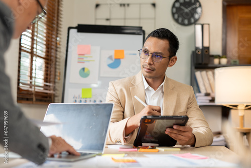 Asian business presents to explain the graph work on the whiteboard. Consulting, discussing, exchanging knowledge.