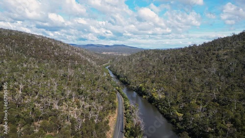 Tasmania, Australia: Aerial drone footage of the road along the Prosser river near Orford in the hills of Tasmania countryside through a dense forest.  photo