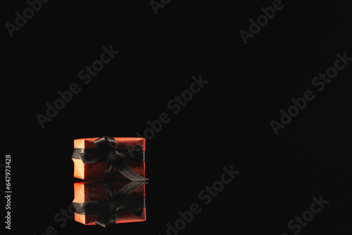 Red gift box with ribbon and copy space over black background