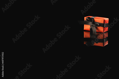 Red gift box with ribbon and copy space over black background