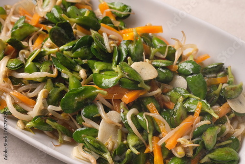 stir-fry bean sprouts, carrots, and katel (soybean shoots). Indonesian food. served in white plate in gray table. Katel is superfood from soybean typical of Majalengka regency. photo