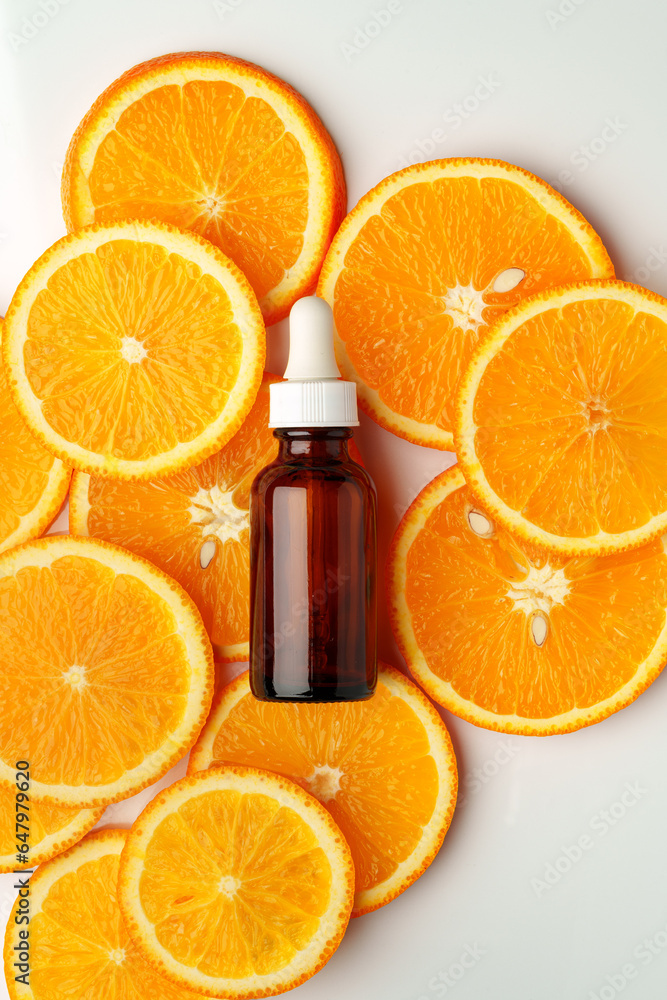 Glass bottle of essential citrus oil on oranges background Glass bottle of essential citrus oil on oranges background