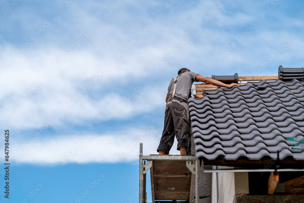 covering the tip of the roof with a ceramic tile by a craftsman, copy space covering the tip of the roof with a ceramic tile by a craftsman, copy space