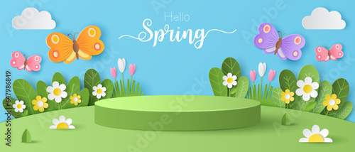 Paper cut of field of flowers and flocks of butterfly on blue sky background with green cylinder podium for your products display presentation. Hello spring.