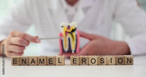 Phrase Enamel Erosion composed of small wooden blocks against female stomatologist showing parts of tooth. Dental problem with enamel