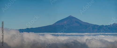 Panoramic aerial view of volcano Pico del Teide and Tenerife island above white clouds seen from La Gomera, Canary Islands, Spain, Europe. © Kristyna
