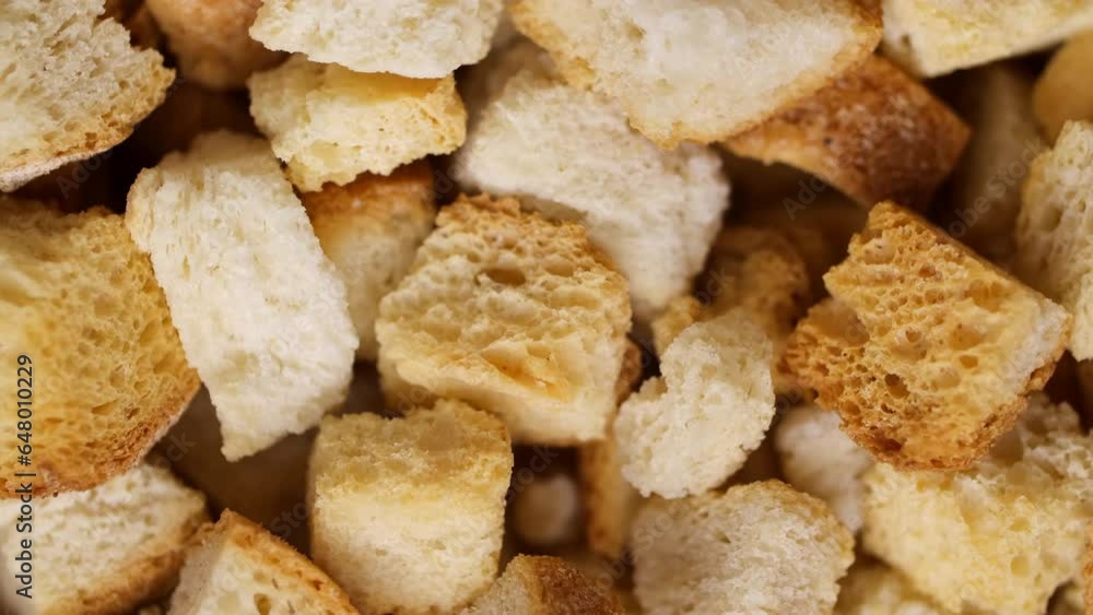 Crispy toasted bread falling down spinning in slow motion. Cubes of toasted bread close-up. Macro shot of bread crumbs. Crispy toasted bread falling down spinning in slow motion. Cubes of toasted bread close-up. Macro shot of bread crumbs.